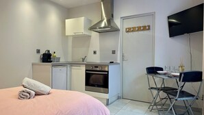 Une chambre compacte comprenant un lit, une petite kitchenette et un coin repas.