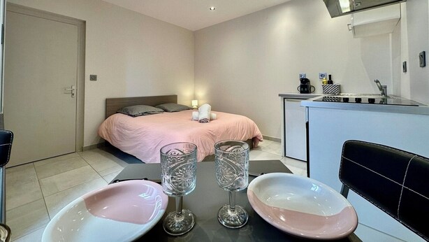 Une chambre d’hôtel de taille réduite comprenant un lit, une kitchenette et un coin repas.