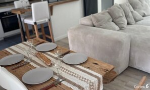 Une table à manger dressée avec des assiettes, des verres et des couverts, un pain et un set de table en fibres tressées.