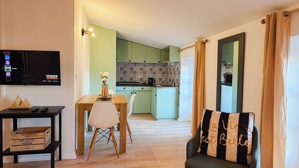 Een moderne woonkamer met een televisie, een eettafel en een bank.