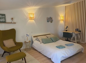 Een slaapkamer met een bed, een bureau, een stoel en wandlampen.