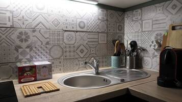 A kitchen with a modern design, featuring a sink, a wooden cutting board, and a box of tissues.