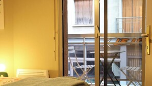 Ein Schlafzimmer mit Bett, einer Schiebetür zum Balkon mit Tisch und Stühlen.