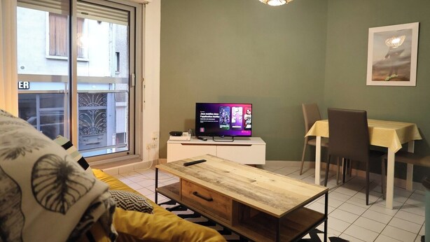 Ein Wohnzimmer mit Fernseher, einem Esstisch und einer Couch.