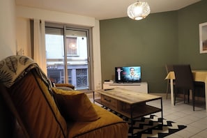 Una sala de estar con un sofá, una mesa de centro, un televisor y un comedor con sillas y una mesa.