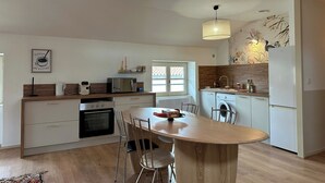 Eine moderne Küche mit Kochinsel, Holzschränken, Backofen, Mikrowelle und Spüle.