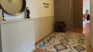 Ein Flur mit einem gemusterten Teppich, einem Wandspiegel, einem Kleiderständer und einer Schiebetür.