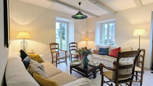 Ein gemütliches Wohnzimmer mit einer Couch, Sesseln, einem Couchtisch und einer Pendelleuchte.