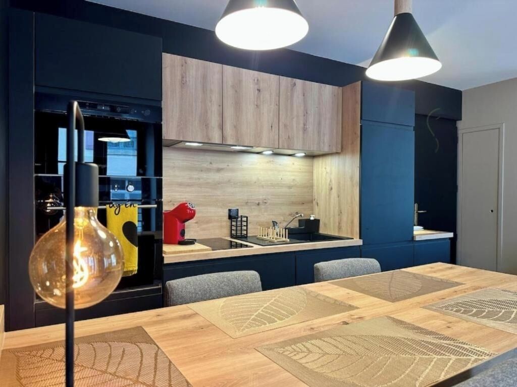 Una cocina moderna con estufa integrada, un fregadero y un comedor con mesa y sillas de madera.