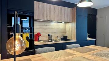 Una cocina moderna con estufa integrada, un fregadero y un comedor con mesa y sillas de madera.
