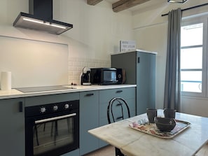 Een moderne keuken met een inbouwoven, magnetron en waterkoker. Boven de magnetron hangt een bordje met de tekst 