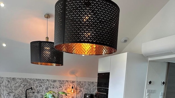 A modern kitchen with a wooden dining table, brown leather chairs, and black pendant lights. - Le rocher des Costes (Le Puy)