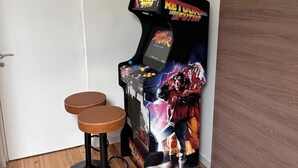 A retro arcade machine with a 'Return to the Future' theme, two stools, and a wooden floor. - Le rocher des Costes (Le Puy)