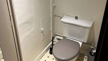 Een kleine, praktische badkamer met toilet, bidet en een prullenbak.