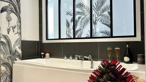 Une salle de bain moderne avec une baignoire, un grand miroir et une décoration florale.