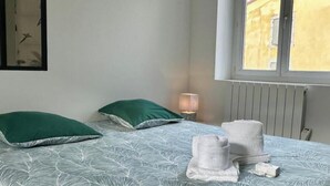 Une chambre à coucher avec un lit, deux oreillers, une lampe de chevet et des serviettes.