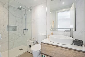 A modern bathroom with a glass-enclosed shower, a white sink, and a large mirror. - Step To The Sea 5, by Pausa Holiday Rentals (Funchal)