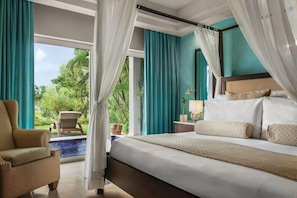 A bedroom with a large bed, a chair, a nightstand, and a view of a pool and greenery. - Dreams La Romana All Inclusive Resort & Spa (San Rafael del Yuma)