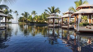 A tranquil pool area with lounge chairs and umbrellas, surrounded by palm trees and a clear sky. - Dreams La Romana All Inclusive Resort & Spa (San Rafael del Yuma)