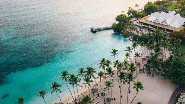 A resort with a beach, palm trees, and a pier. - Dreams La Romana All Inclusive Resort & Spa (San Rafael del Yuma)