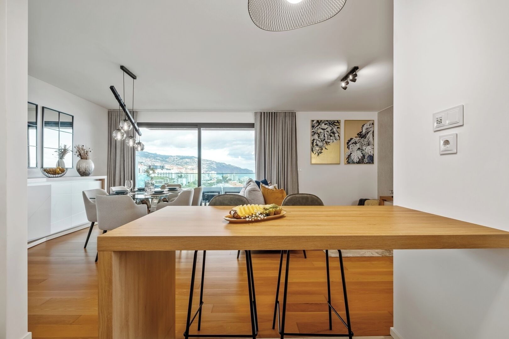 A modern dining area with a wooden table, chairs, and a view of the city.
