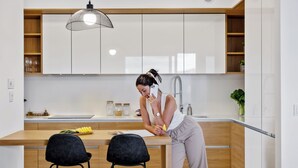 A modern kitchen with white cabinets, a wooden countertop, and a hanging pendant light. - Ajuda I - Penthouse by Pausa Holiday Rentals (Funchal)