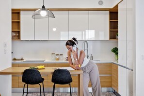 A modern kitchen with white cabinets, a wooden countertop, and a hanging pendant light. - Ajuda I - Penthouse by Pausa Holiday Rentals (Funchal)