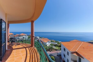 Un balcone con vista sul mare, pavimento piastrellato e un tavolo con sedie.