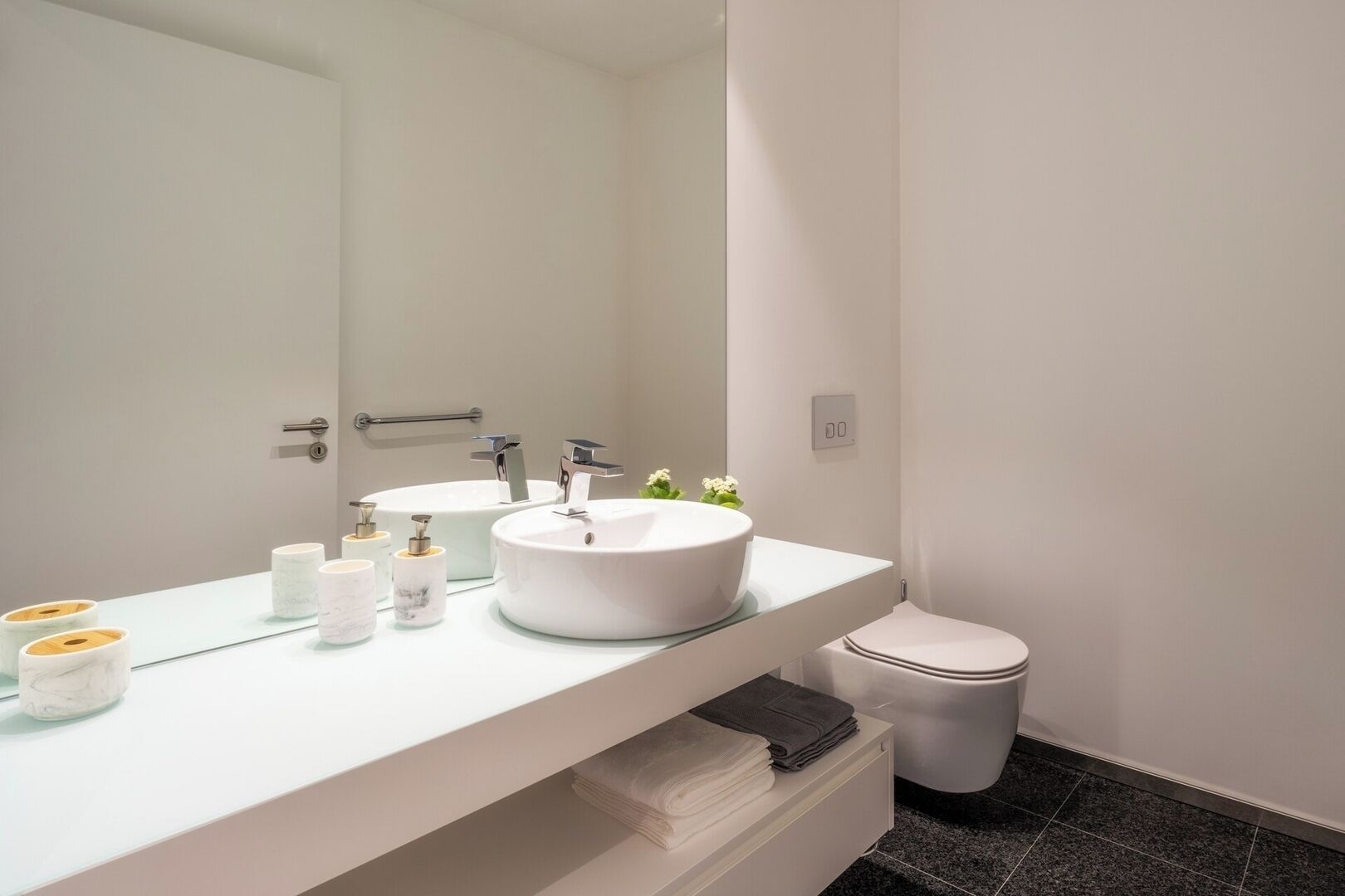 Une salle de bain moderne avec deux lavabos, des toilettes et un miroir.