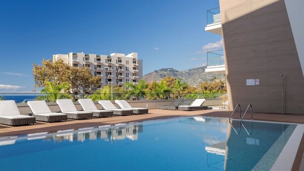 Una piscina amb gandules i vista d'un edifici amb balcons.