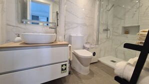 Ein modernes Badezimmer mit einem großen, weißen Waschbecken, einer Toilette und einer Duschkabine.