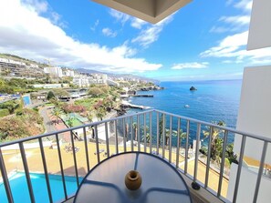 A balcony with a view of a coastal city, a pool, and a clear sky. - Step To The Sea 4, by Pausa Holiday Rentals (Funchal)