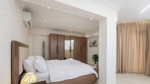 Ein modernes Schlafzimmer mit einem großen Bett, Einbauschränken, einem Nachttisch und einer Topfpflanze.