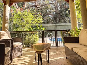 A covered outdoor seating area with wicker furniture and a view of a swimming pool.