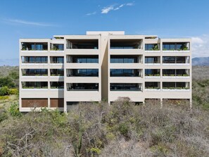 A modern multi-story building with balconies, surrounded by dry vegetation. - Condo Cuenco in Punta Mita (Punta de Mita)