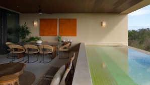 Et udendørs spiseområde med pool, træloft og to vægmonterede lamper.