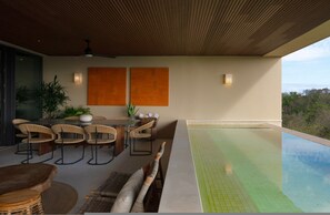 An outdoor dining area with a pool, wooden ceiling, and two wall-mounted light fixtures. - Condo Cuenco in Punta Mita (Punta de Mita)