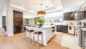 A modern kitchen with a central island, wooden chairs, and a hanging light fixture. - Sierra Roja| Heated Pool, Spa, Gym, Sauna, Theater (Sedona)