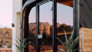A modern building with a large glass door, wooden exterior, and two potted plants on the porch. - Sierra Roja| Heated Pool, Spa, Gym, Sauna, Theater (Sedona)