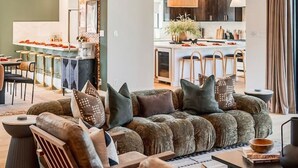 A modern living room with a sectional sofa, wooden chairs, a coffee table, and a dining area with a bar. - Sierra Roja| Heated Pool, Spa, Gym, Sauna, Theater (Sedona)