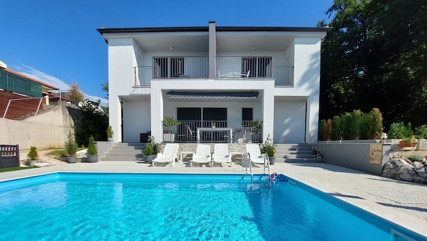A modern two-story house with a swimming pool, white exterior, and a balcony with outdoor furniture. - Villa Madlen - Deluxe Poolside Apartment (Opatija)