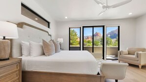 Un dormitorio moderno con una cama grande, ventilador de techo y vistas al exterior.