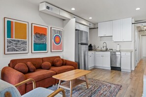 Un apartamento moderno con sala de estar, kitchenette y un sofá con cojines.