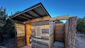 A rustic cabin with a wooden exterior, a stone wall, and a metal roof.