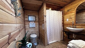 A wooden cabin bathroom with a sink, toilet, and shower curtain.