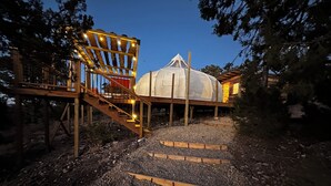 A wooden deck leading to a white tent-like structure with a staircase and railings.