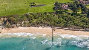 An aerial view of a coastal area with a sandy beach, a wooden pier, and residential buildings in the background. - Holmes House - Sleeps 20 -Swimming pool -Sea Views (Colwell Bay)