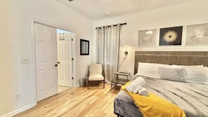 Ein Schlafzimmer mit Bett, Stuhl, Nachttisch und Tür.