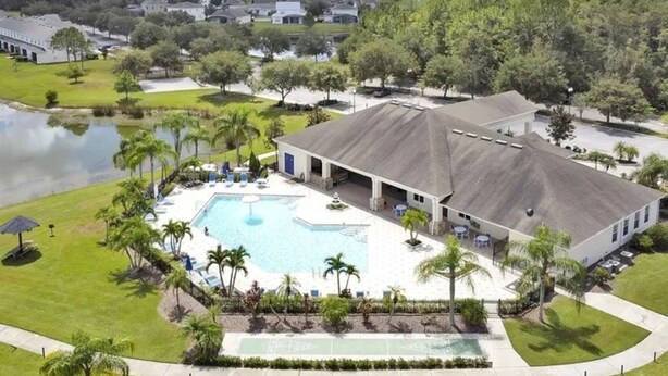 A large building with a swimming pool, surrounded by palm trees and a lake. - 2632 Remodeled Getaway -heart of Disney (Kissimmee)