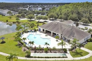 A large building with a swimming pool, surrounded by palm trees and a lake. - 2632 Remodeled Getaway -heart of Disney (Kissimmee)